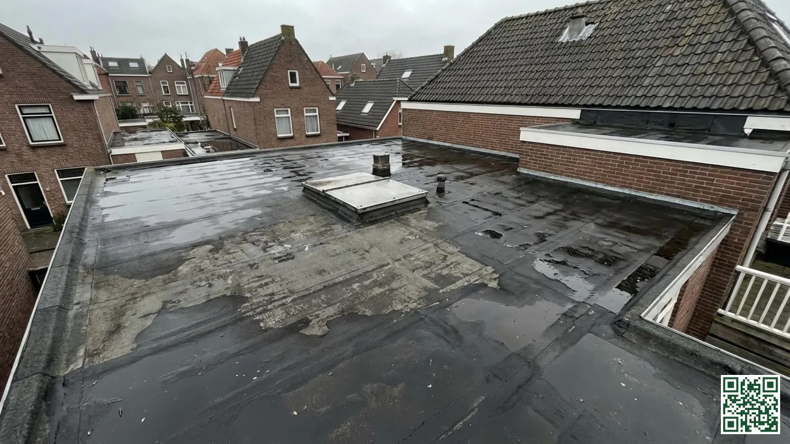 Plat dak met zwarte bitumen dakbedekking op Nederlandse woning met zichtbare dakranden